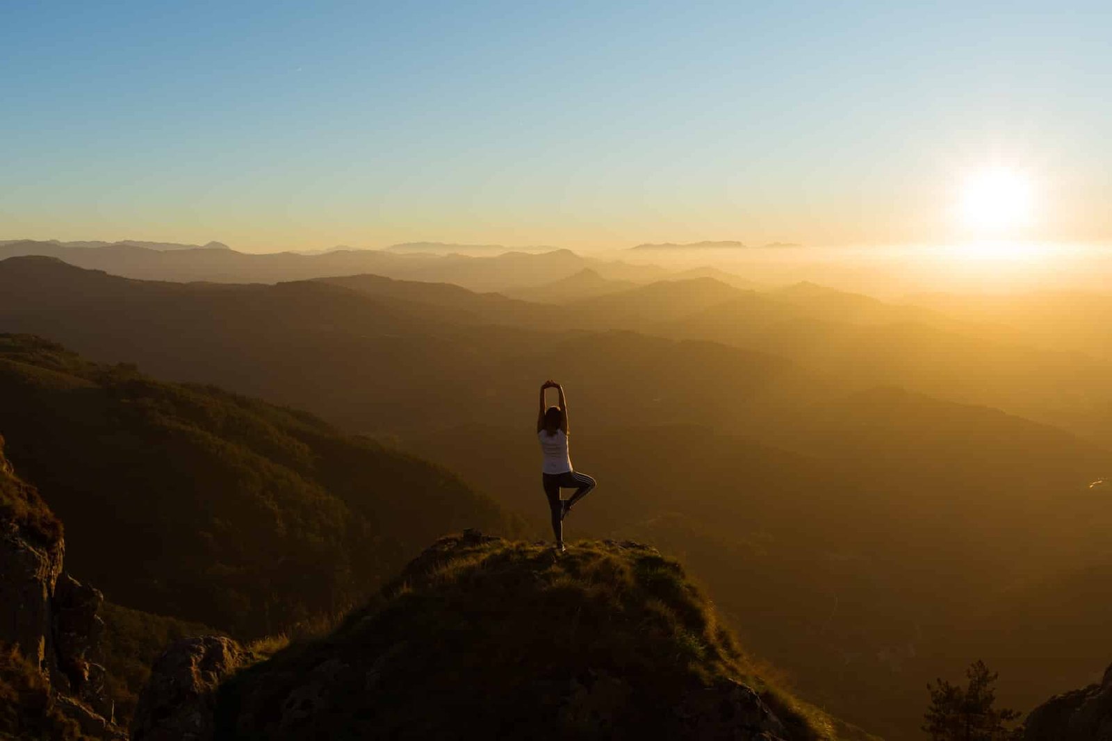 Someone doing yoga on a mountain with the sun rising